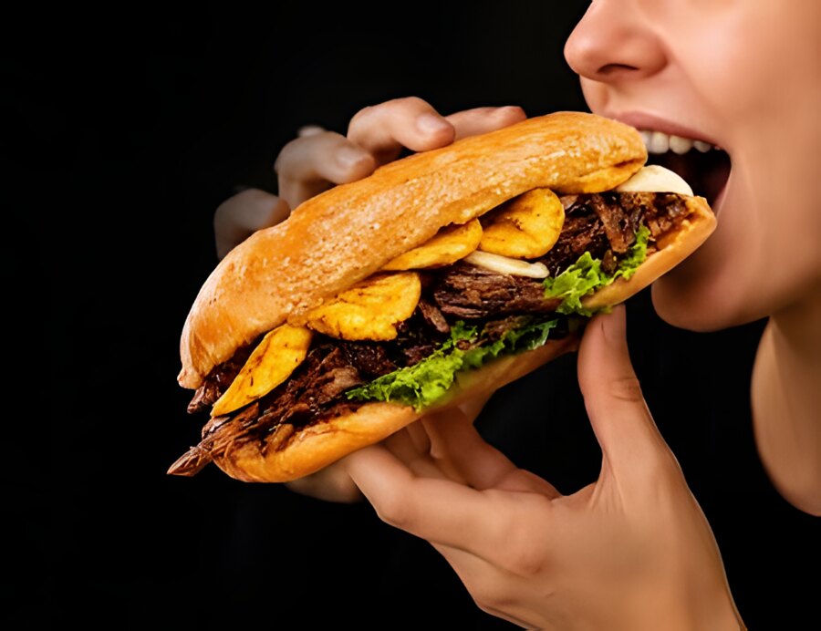Alguien mordiendo un sánduche de CARNUDOS: carne desmechada, maduritos y queso en pan brioche